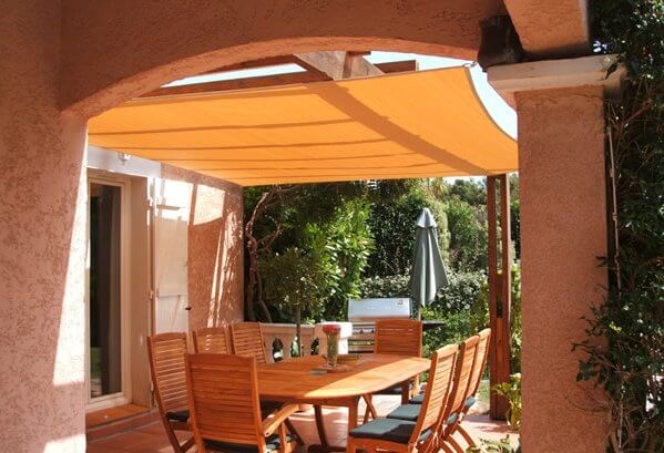 Vela de sombra transpirable sobre una terraza con pérgola